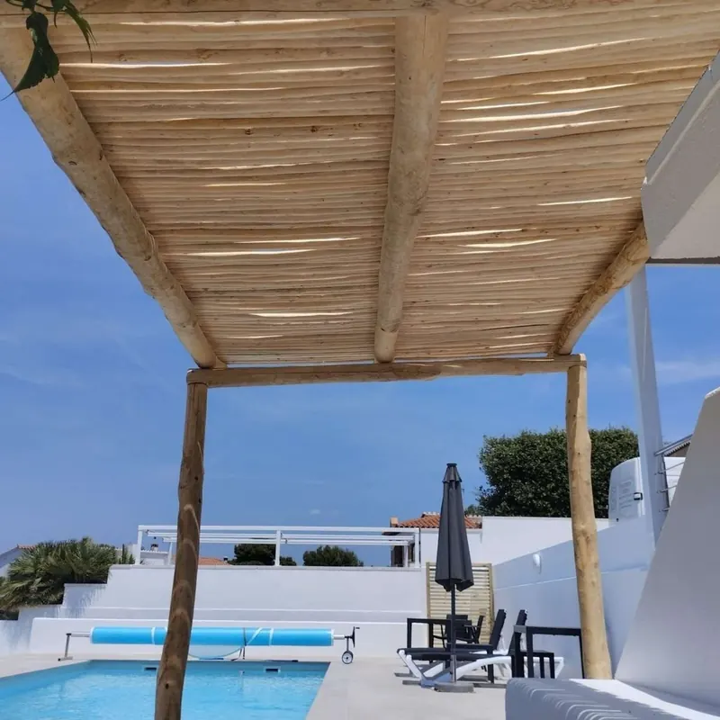 Pérgola de palos de eucalipto junto a una piscina