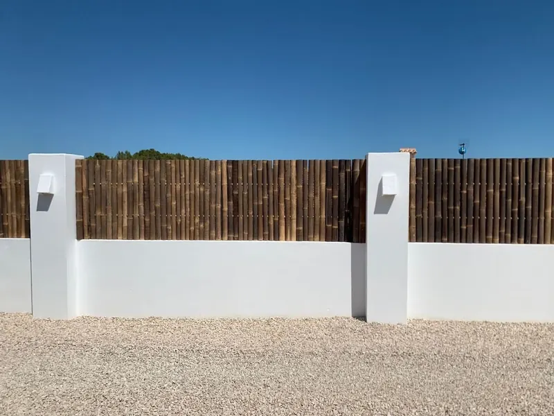 Vallado decorativo de palos de eucalipto sobre un muro blanco