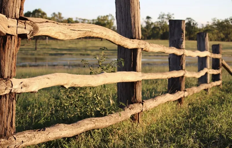 Vallado rural de postes y travesaños de eucalipto en un prado
